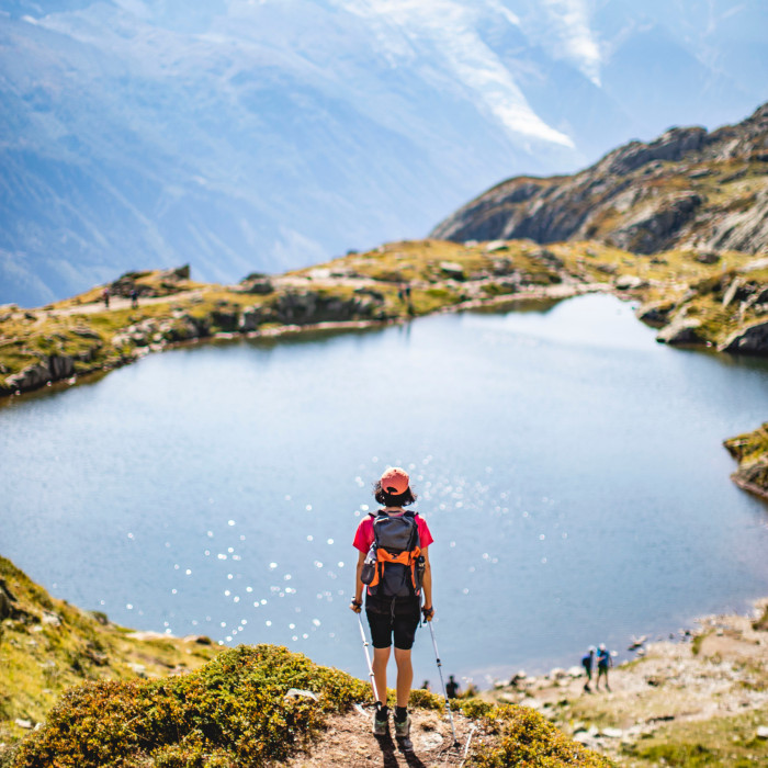 Hiker looking over a mountain lake from above with mountains in the background